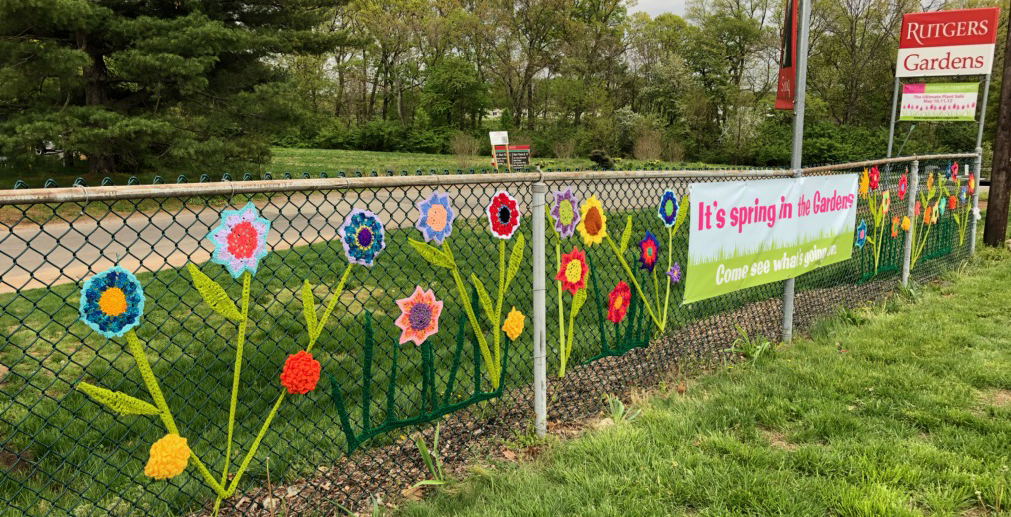 chain link fence decorated with crocheted yarn flowers