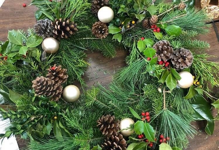 evergreen wreath decorated with sprigs of holly and pinecones