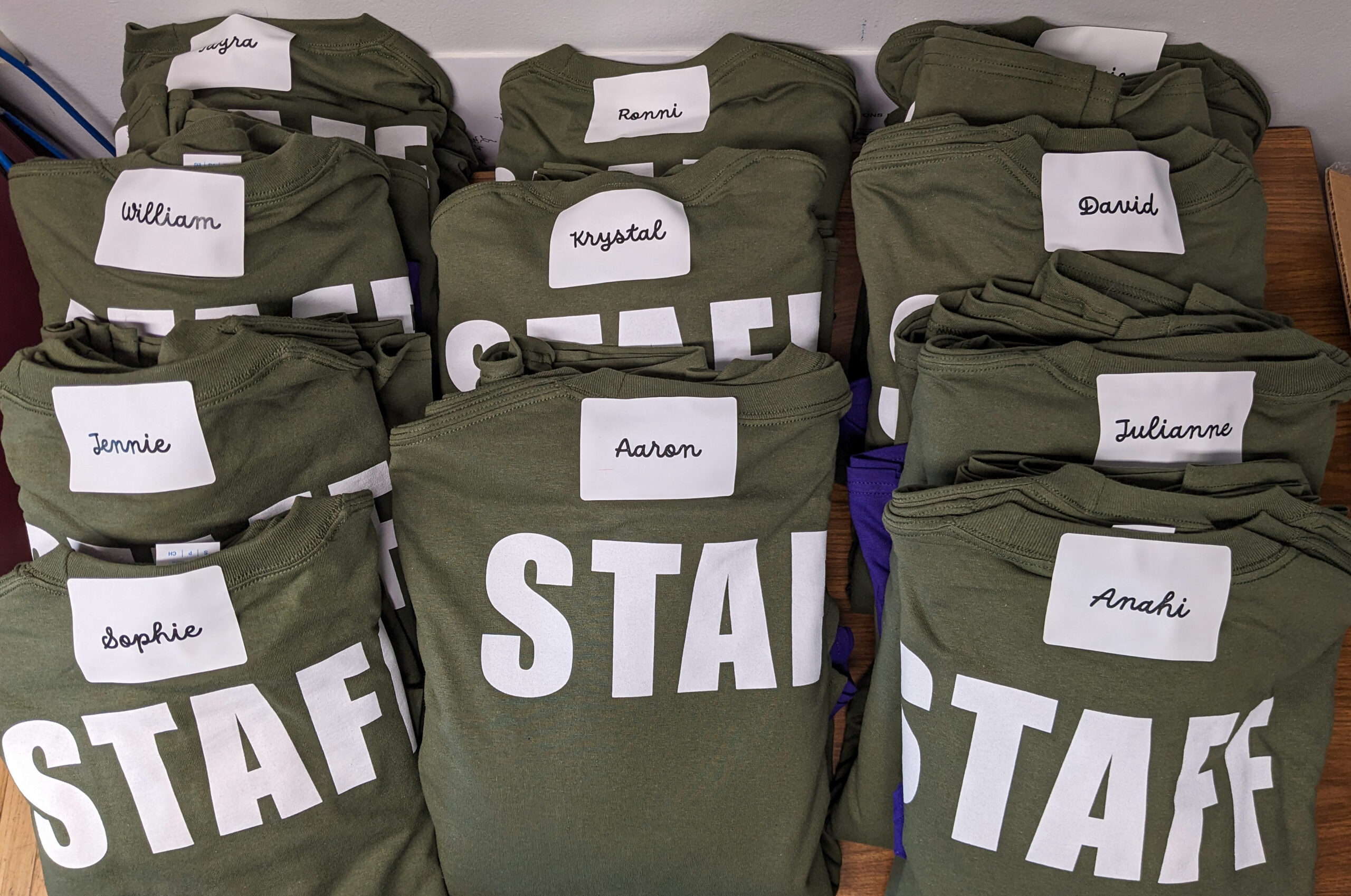 Green shirts for student Staff are labeled with interns' names.
